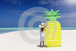 Summer concept with a little girl holding a pineapple shaped floaty