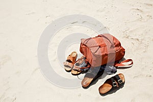Summer concept, things on beach sand, male and female flops and brown sports backpack. Flat lay. Copy space