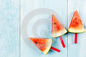 Summer concept watermelon slice popsicles on a blue rustic wood