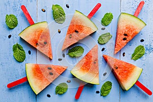 Summer concept watermelon slice popsicles on a blue rustic wood