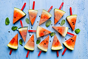 Summer concept watermelon slice popsicles on a blue rustic wood