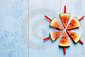 Summer concept watermelon slice popsicles on a blue rustic wood