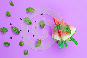 Summer concept watermelon slice popsicles on a pink background