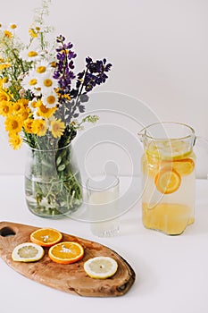 Summer concept. Wild flower bouquet on the table. Homemade lemonade with oranges and lemons. Healthy and fresh, tasty cool beverag