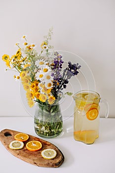 Summer concept. Wild flower bouquet on the table. Homemade lemonade with oranges and lemons. Healthy and fresh, tasty cool beverag