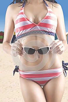 Woman in swimsuit holds sunglasses