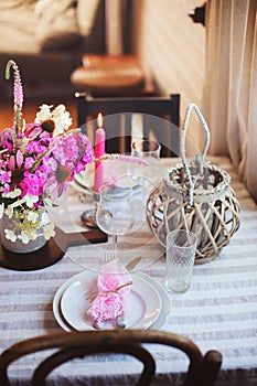 summer cottage kitchen decorated for festive dinner. Romantic table setting with candles and flowers