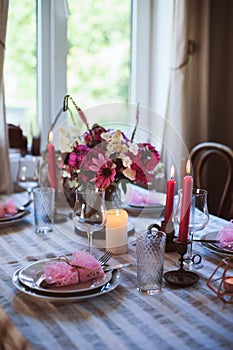 Summer cottage kitchen decorated for festive dinner. Romantic table setting with candles and flowers