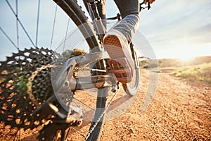 Summer, cycling and a man on a bike and dirt road for fitness, morning cardio or adventure in nature. Sports, feet and a