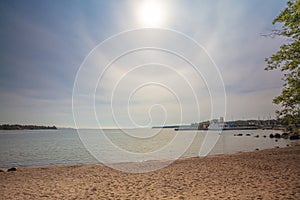 On a summer day, the beach on the Gulf of Finland. A halo around the sun