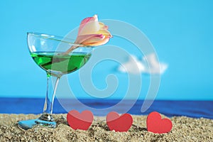 Summer day with cool cocktail on sea beach with red heart