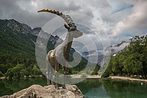 Summer day at lake Jasna in Kranjska Gora guarded by statue of a capra ibex