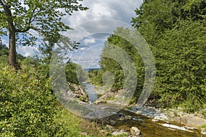 Summer day landscape with river, forest and cloudy sky