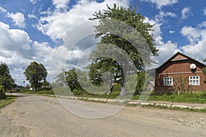 Summer day landscape with road, cloudy sky and small houses. Ukraine, Carpathian.