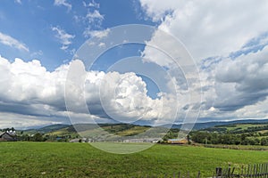 Summer day landscape with road, cloudy sky and small houses. Ukraine, Carpathian.