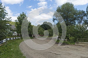 Summer day landscape with road, cloudy sky and small houses. Ukraine, Carpathian.