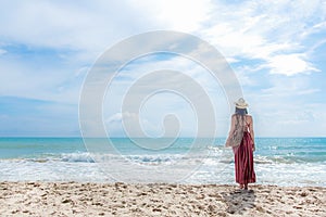 Summer Day. Smiling woman wearing fashion summer standing and see the sandy ocean beach. Happy woman enjoy and relax vacation.