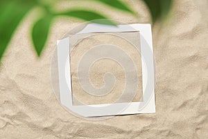 Summer design, sand background, tropical leaf and paper frame: beach, vacations