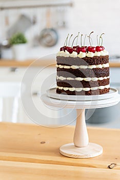 Summer dessert with cherries. Naked chocolate cake on the kitchen table. Holiday concept. Happy birthday card. Schwarzwalder
