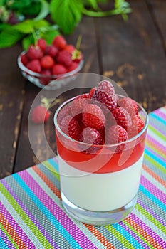 Summer dessert with cream and raspberry jelly, decorate with fresh berries in a transparent glass