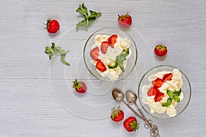 Summer dessert with sliced strawberries and cream cheese in the glass bowls on a gray background with copy space. Parfait