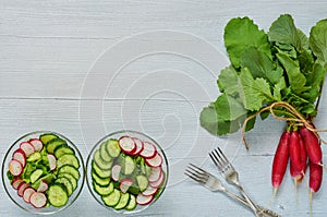 Summer detox salad with radish, cucumber and spinach in two glass bowls on the gray kitchen table with copy space