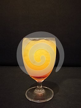 Summer drink, fresh orange juice, mocktail with soda and ice cube, soft drink with ice on glass with blur isolate black background
