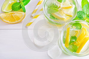 Summer drink mojito with lime, lemon and mint, with ice cubes on white wooden background. Flat-lay, top view