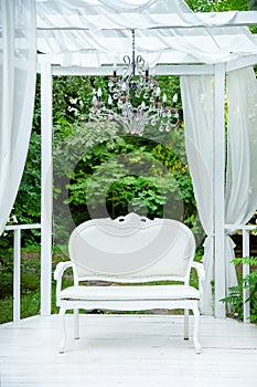 Summer elegant elegant gazebo in the lush gardens. Exquisite classic sofa gazebo