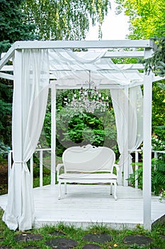 Summer elegant elegant gazebo in the lush gardens. Exquisite classic sofa gazebo