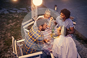 Summer evening in the garden, a group of friends  have a good time smiling together around a table