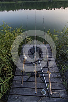 Summer evening on lake with fishing roads on the bridge