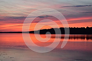 Summer evening red sunset over the river clouds and water surface