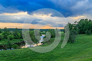 Summer evening, the river flows through a field