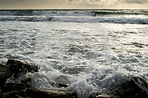 Summer evening on the rocky shore of the stormy sea