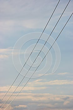 Summer evening sky background, vertical bright blue skyscape copy space, three power line cable wires, pink pastel clouds