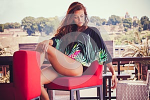 Summer fashion girl in tunic and bikini at pool cafe