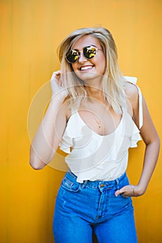 Summer, fashion and people concept - bright stylish portrait pretty woman in sunglasses against colorful wall in the city