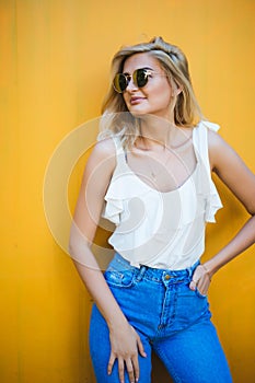 Summer, fashion and people concept - bright stylish portrait pretty woman in sunglasses against colorful wall in the city