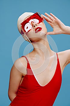 Summer fashion shooting. A sophisticated red-lipped lady in a swimming cap and a red swimsuit touches her glasses and