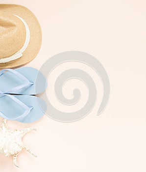 Summer fashion, summer outfit on cream background. Blue flip flops, seashell and straw hat. Flat lay, top view.