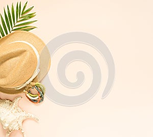 Summer fashion, summer outfit on cream background. Seashell, wood bracelet and straw hat. Flat lay, top view.