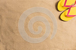 Summer fashion, summer outfit on sand background. Yellow flip flops aon the sand