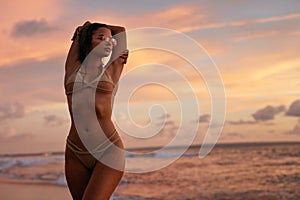 Summer fashion. Woman with body in swimsuit on beach with sunset