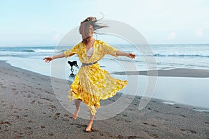 Summer Fashion. Woman In Bohemian Clothing Walking With Dog On Beach. Beautiful Model In Maxi Dress