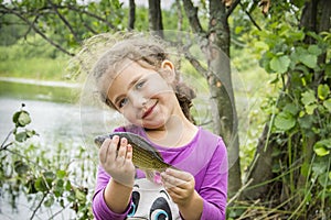 In the summer on a fishing little girl caught a large carp.