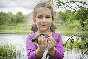 In the summer on a fishing little girl caught a large carp.