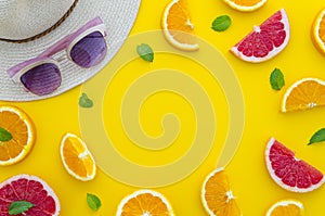 Summer composition arranged in a frame of sliced citrus fruits with little mint leafs, a summer hat and sun glasses on