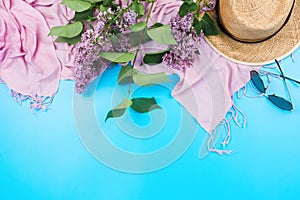 Summer flatlay with pink scarf, straw hat and sungasses on blue