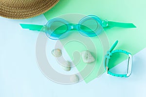 Summer flatlay with watersport goggles, hat, watch on mint and light blue background, minimalistic style, copy space